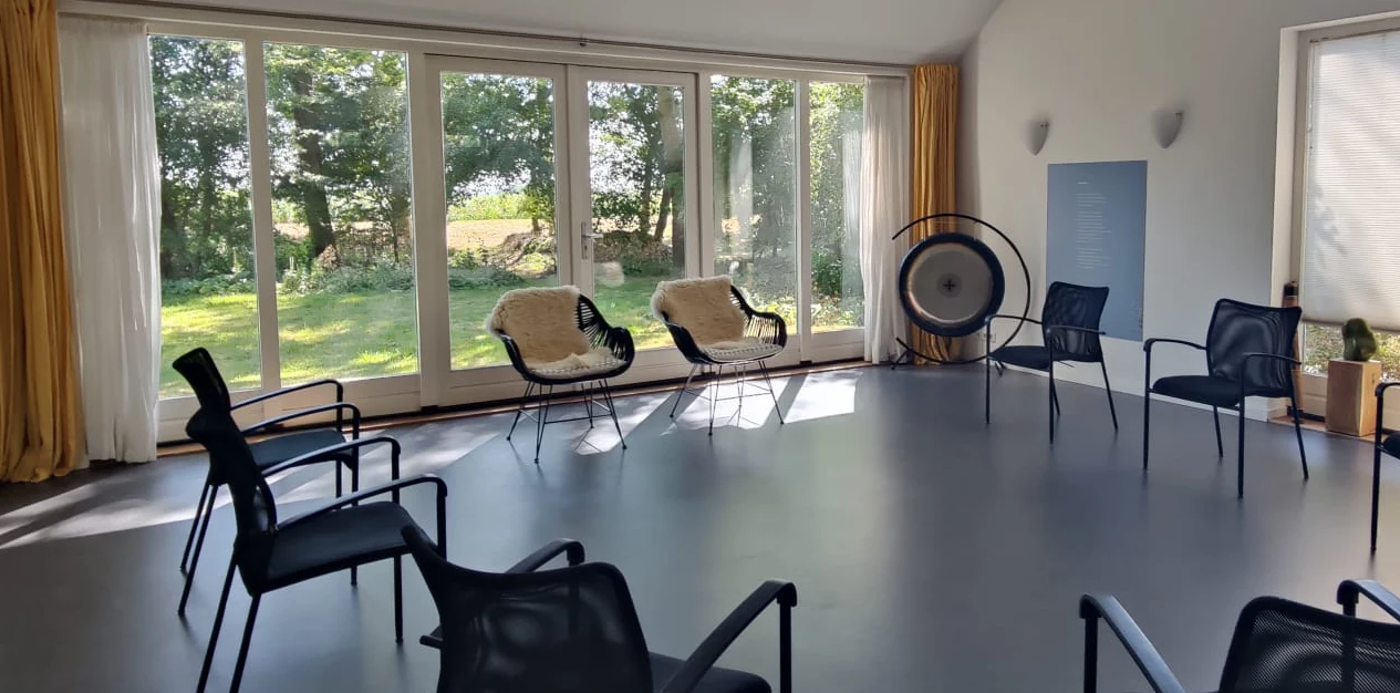 De ruimte in de Berkeley: stoelen in een kring, uitzicht op de tuin en een gong